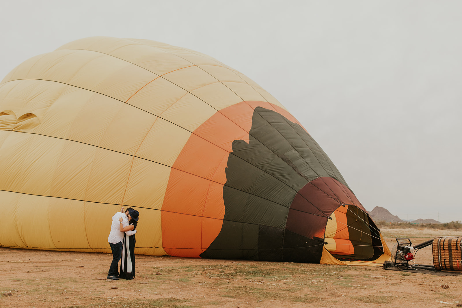 Happy couple takes fun engagement pics by hot air balloon.